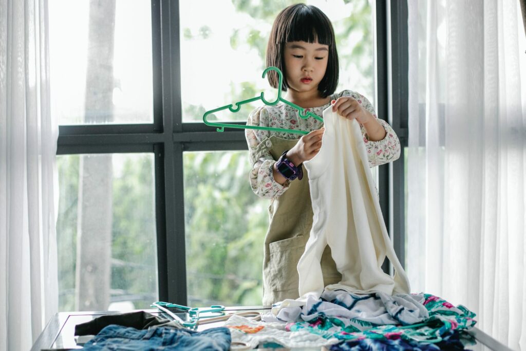 A little girl hanging up her clothes